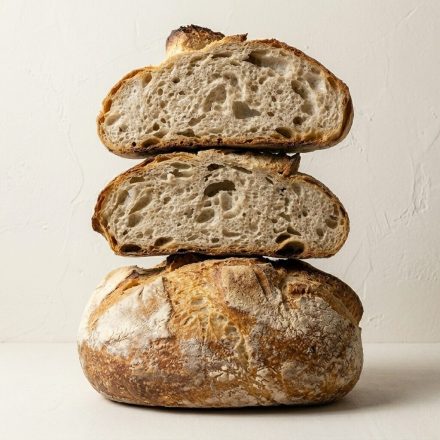 Pan de Porriño artesano gallego con corteza dorada y miga alveolada. Hogaza entera y cortada mostrando su interior.