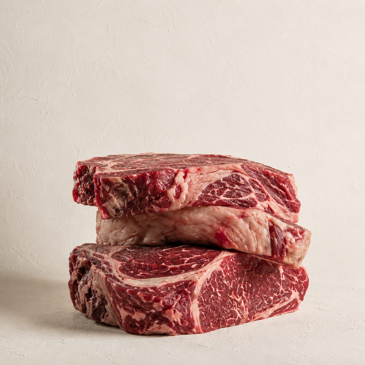 Composición artística de cortes de carne Rubia Gallega Halal cruda sobre una superficie oscura, resaltando la textura de la pieza.